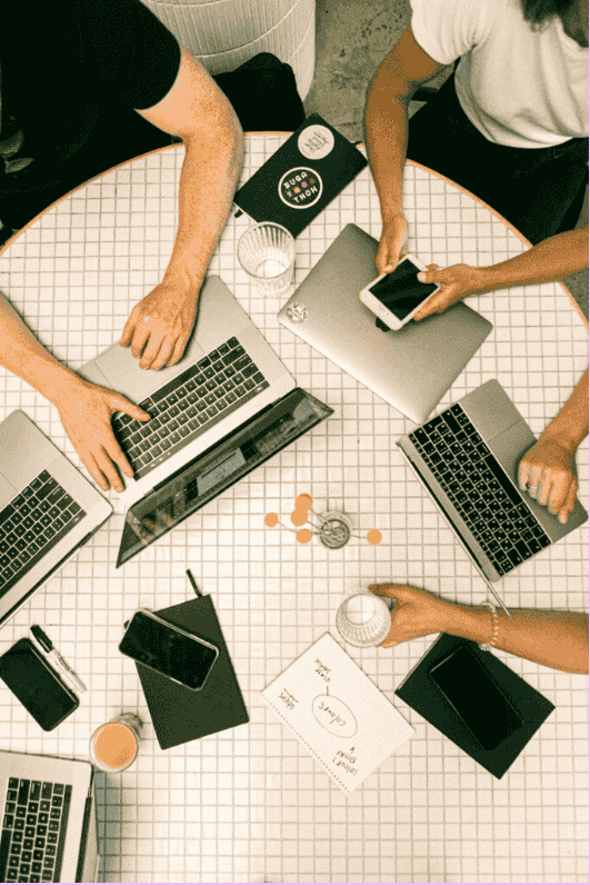 Team collaborating with laptops and phones around a table, brainstorming ideas at a content marketing agency in Chandigarh.