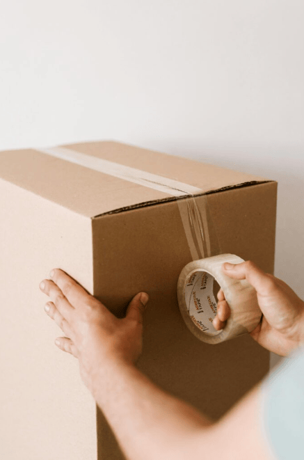 Hands sealing a cardboard box, symbolizing dropshipping services by a dropshipping marketing agency in Chandigarh.